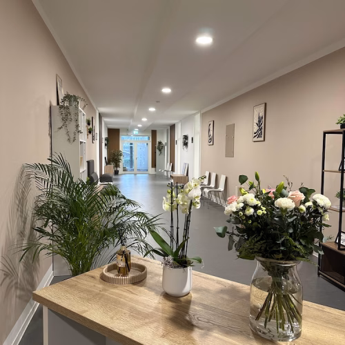 Einladender Praxisflur der Therapiepraxis Wittenburg in Rheine mit Empfangstresen, frischen Blumen und hellem Wartebereich